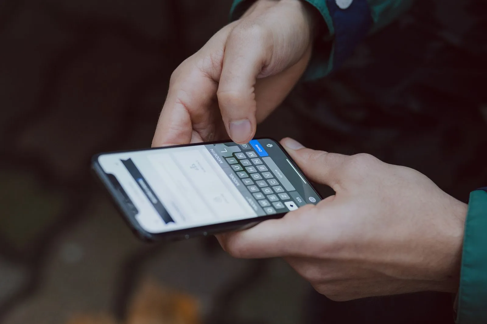 Mãos de uma pessoa digitando uma mensagem na tela de um celular
